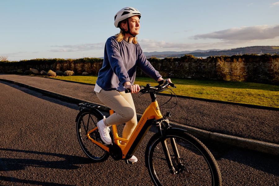 Hände schlafen beim Radfahren ein: Frau fährt auf gelbem E-Bike
