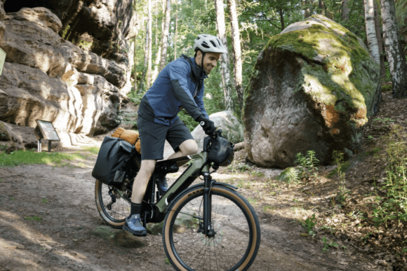 Bikepacking: Mann mit bepacktem E-Bike fährt Fahrrad im Wald