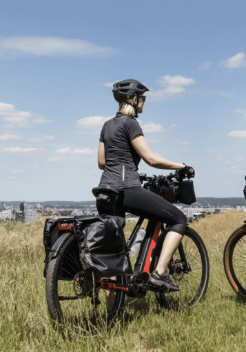Bikepacking: Frau mit E-Bike und Taschen genießt die Aussicht(470)