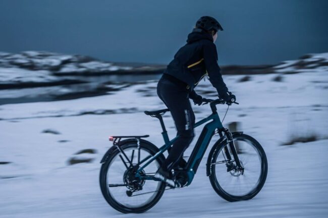 Frau fährt E-Bike an einem Winterabend