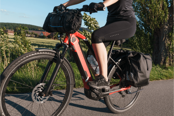 Welche Muskeln werden beim Radfahren trainiert: Frau auf rotem E-Bike tritt in die Pedale