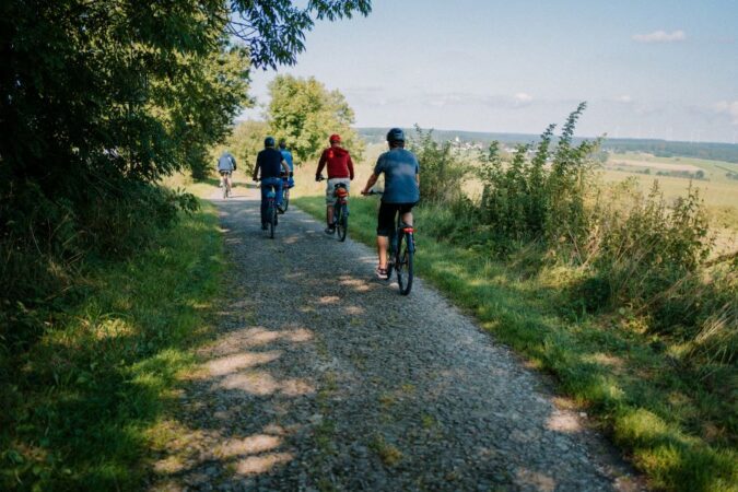 Fahrradtour planen: Radgruppe fährt am Waldrand