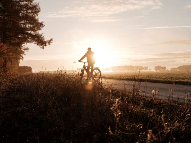 mann fährt fahrrad bei sonnenuntergang